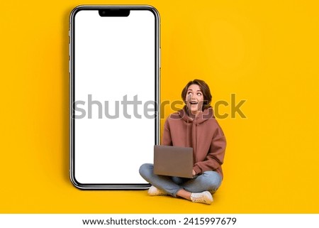 Full size photo of young beautiful woman use laptop look curious smartphone screen electronic panel ad isolated on yellow color background