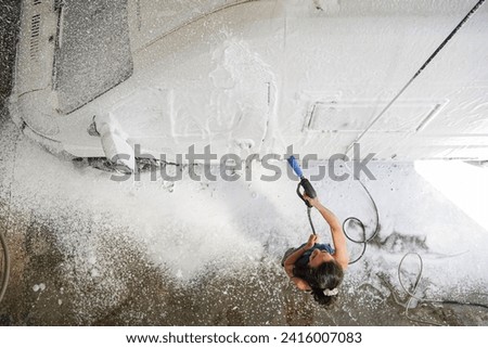 Top view of a woman cleaning the car in a car wash
