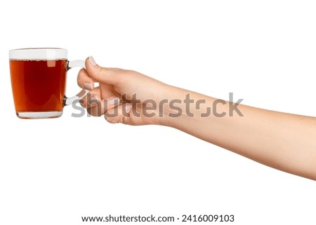 A woman's hand holds a cup of black tea with bergamot in a transparent glass cup. On a blank background