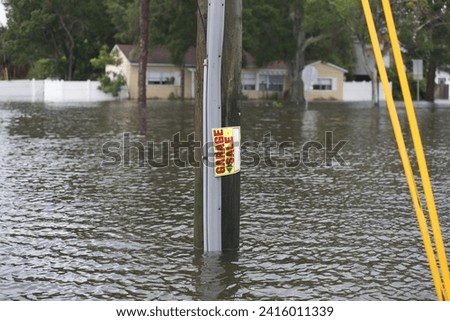 A garage sale sign at an intersection covered with storm surge by Hurricane Idalia in Shore Acres, a neighborhood in St. Petersburg, Florida.