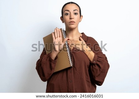 beautiful arab student carries notebooks with paper Swearing with hand on chest and open palm, making a loyalty promise oath