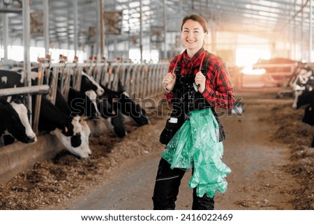 Portrait happy young woman veterinarian doctor with stethoscope and disposable gloves for rectal examination on cow farm. Concept worker cattle livestock farming industry. Royalty-Free Stock Photo #2416022469