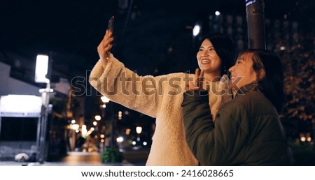 Japanese, women and selfie outdoor at night with hand gesture, peace sign and happy in city street. Friends, people and phone with smile for travel, adventure and social media update in urban town