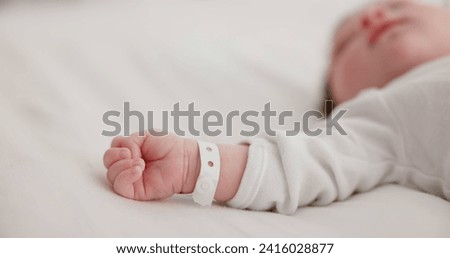 Baby, new born and hand with bracelet on bed for care, trust or support in hospital for birth. Infant, love and hope with child development for future growth in family home, protection and security Royalty-Free Stock Photo #2416028877