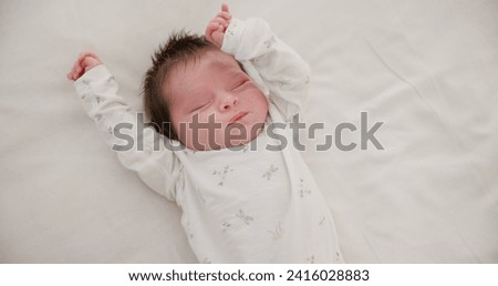 Newborn, face or sleeping with stretching on bed in nursery for relaxing or resting with child development. Baby, tired or dreaming in bedroom of house with calm, relax and cute infant in family home Royalty-Free Stock Photo #2416028883