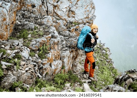 The guy climbed the rock alone, mountain hiking extreme sport, hard climbing, hiking with a backpack in the mountains, trekking. High quality photo
