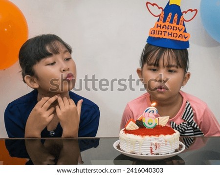 Siblings joyfully celebrate sister's 6th birthday, pleasantly surprised with her birthday cake, pure happiness radiates