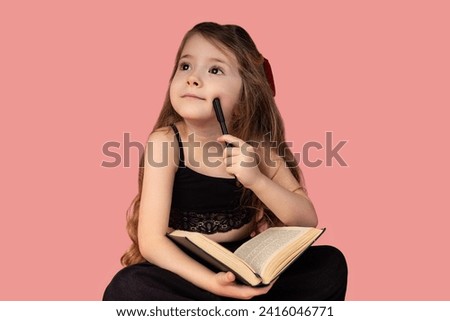 Picture on a pink background with a very beautiful and chubby little girl, the little girl likes to read books and is chubby and thinking while holding a pen to her cheek.