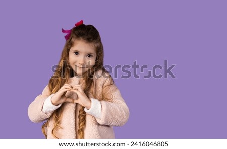 A picture used for a banner with a little blonde girl showing us a very original heart from her hands. The girl has an attractive smile and very beautiful brown eyes.