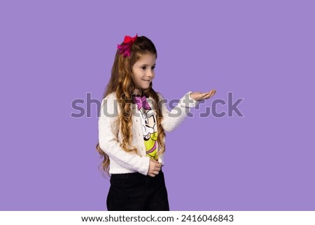 A very beautiful little girl with an attractive and wonderful smile points her hand at an object, the picture is taken to be used for a banner or advertisement, the girl is attractive and attracts a