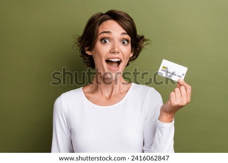 Photo portrait of pretty young girl hold excited credit card bank client wear trendy white outfit isolated on khaki color background