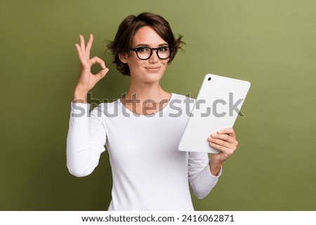 Photo portrait of lovely young lady hold tablet show okey symbol wear trendy white garment isolated on khaki color background