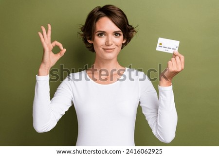 Photo portrait of attractive young woman hold credit card show okey symbol wear trendy white clothes isolated on khaki color background