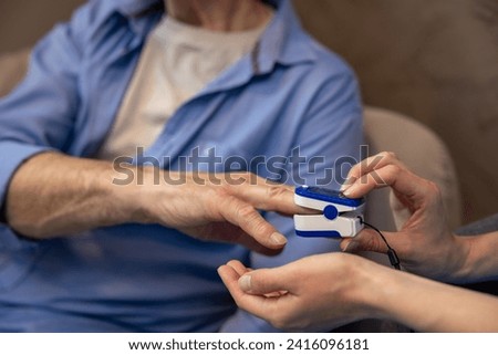 Nurse checking pulse or level of oxygen using oximeter of unrecognizable senior man. Royalty-Free Stock Photo #2416096181