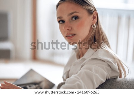 Confident blonde woman relaxing at home sitting with book.