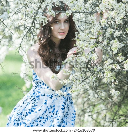 Beautiful european girl with light skin and long brunette hair spends her free time in the blooming park in spring