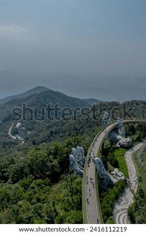 Aerial view of the Golden Bridge in Ba Na hills, Da Nang, Vietnam. Lifted by two giant concrete hands. Iconic world famous bridge in the mountains Royalty-Free Stock Photo #2416112219