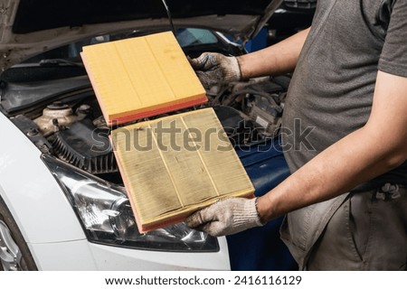 Auto mechanic shows old and new engine air filter for a passenger car