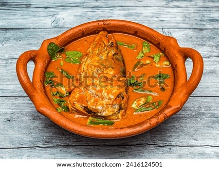fish head curry served in clay pot isolated on wooden table top view of indian spicy food