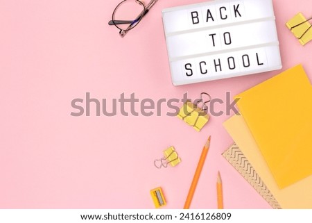 Back to school. Lightbox with letters and stationery on a pink background. Concept with copy space.