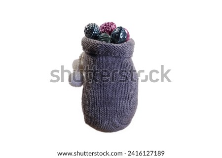 Knitted bag filled with Christmas tree toys on a white background.