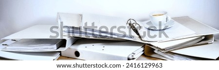 Messy office desk full of ring binders and a coffee cup, wide panoramic format, business concept for stress and overload at work, copy space, selected focus, narrow depth of field Royalty-Free Stock Photo #2416129963