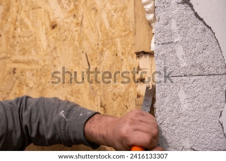 Expert Artisan meticulously shapes wood, creating precise notches with chisel and hammer, transforming and renovating the room. Royalty-Free Stock Photo #2416133307