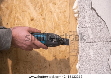 A skilled Craftsman demonstrates precision, making notches in a wooden frame on the wall using a multicutter during room renovation.
