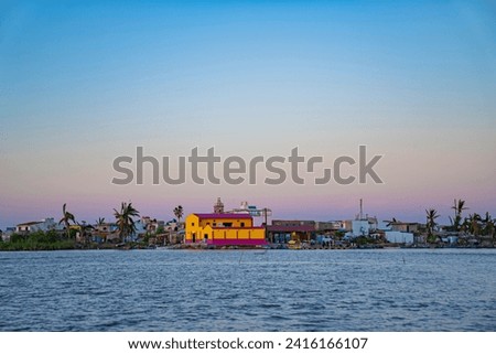 beautiful island of Mexcaltitan surrounded by water channels of the Laguna Grande with the clear sky and the sunset in the background