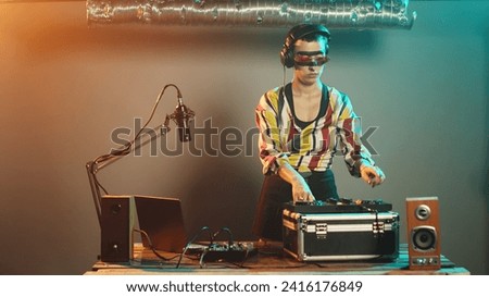 Talented disc jockey using vinyl to mix music at turntables, creating remix of modern records at electronic instrument. Mixing with audio control panel on nightclub stage. Tripod shot.