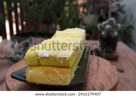 Delicious Classic Lemon Pound cake with grated cheese sprinkles and lemon sauce dripping on top on a wooden background. Two Layer of lemon cake with yellow syrup topping.