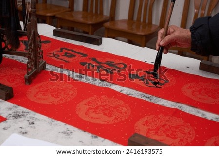 An old calligrapher writes couplets during the Chinese Year of the Dragon.
Translation: Spring fills the world.