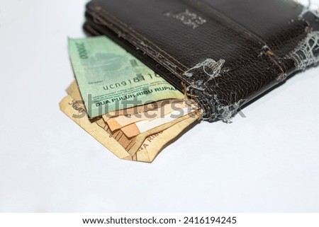 Damaged wallet displaying torn edges and containing a piece of money