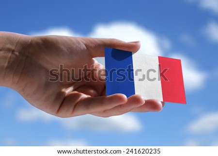 Small French flag against sky with cumulus clouds