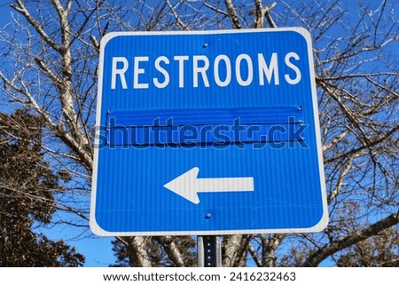 Blue restroom sign posted at highway rest area.