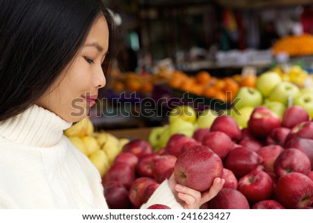 Close up portrait of a young woman at store with apples in hand