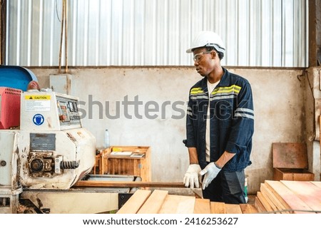 Caucasian male Professional and skillful carpenter or worker is working with hardwood, timber or wooden pallet material for furniture production factory industry. Technician wears hardhat for safety.