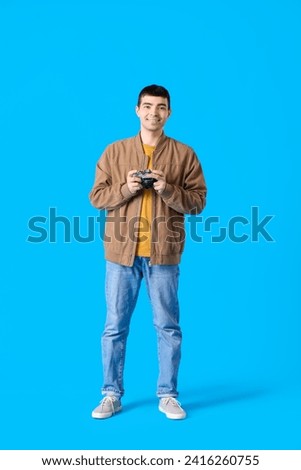 Young male photographer with retro camera on blue background