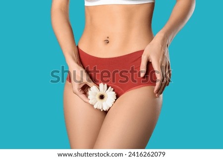 Young woman in panties with beautiful white flower on blue background