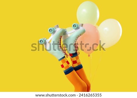 Balloons and legs of woman in roller skates on yellow background