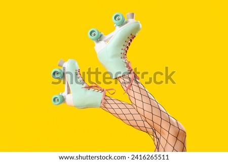 Legs of woman in roller skates on yellow background Royalty-Free Stock Photo #2416265511