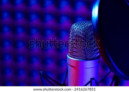 Professional studio microphone against acoustic foam panel background in neon light