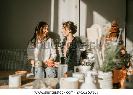 Time for intimate conversations: two women drinking tea in the sunshine in a cozy environment Girls friends talking over a cup of coffee Royalty-Free Stock Photo #2416269187