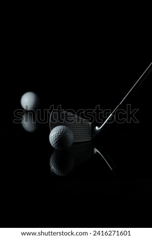 photo of a golf stick with the focus set on the golf ball in front of the stick and with a dark background