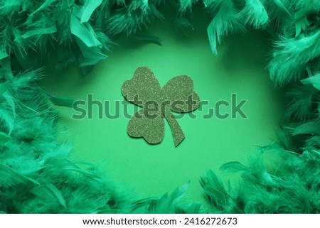 Paper clover with feathers on green background. St. Patrick's Day celebration