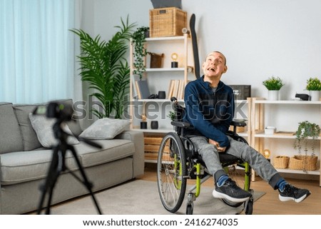 Disabled man recording a video tutorial at home using a digital camera and tripod