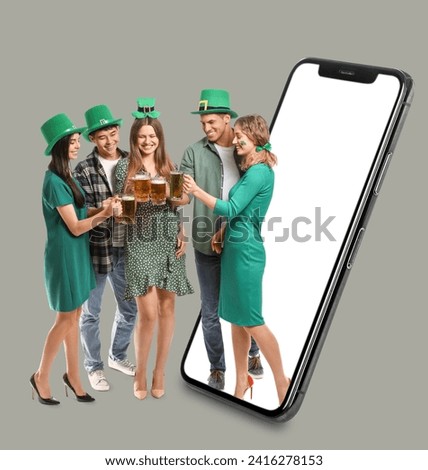 Big smartphone and happy friends with beer on grey background. St. Patrick's Day celebration