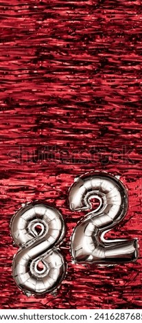 Silver foil balloon number 82 on a background of red tinsel decoration. Birthday greeting card, inscription eighty-two. Anniversary event. Vertical Banner. copy space.