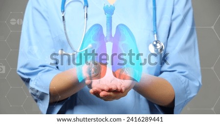 Female doctor using virtual screen with picture of lungs on grey background
