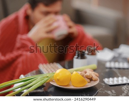 Ginger, lemon, onion and different drugs on table on background sick man. Alternative remedies and traditional pills to treat colds and flu. Natural medicine vs conventional medicine concept Royalty-Free Stock Photo #2416290449